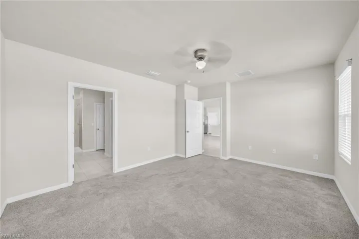 Unfurnished bedroom with light carpet and ceiling fan
