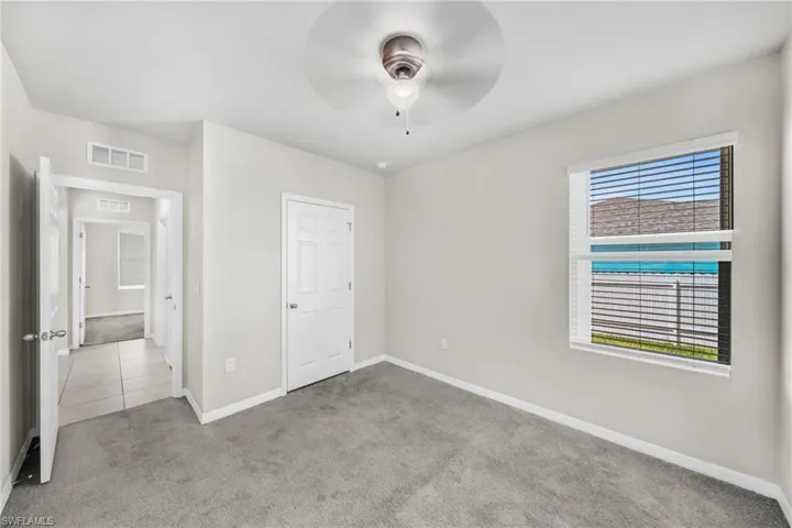 Unfurnished bedroom with light colored carpet and a ceiling fan