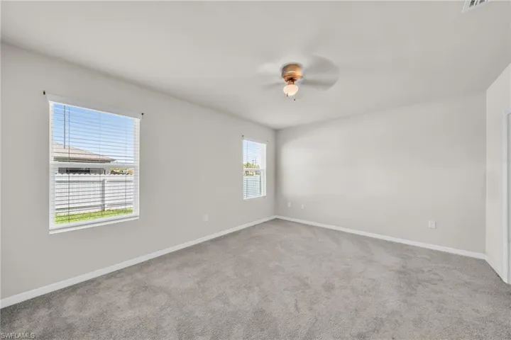 Unfurnished room with light colored carpet and ceiling fan