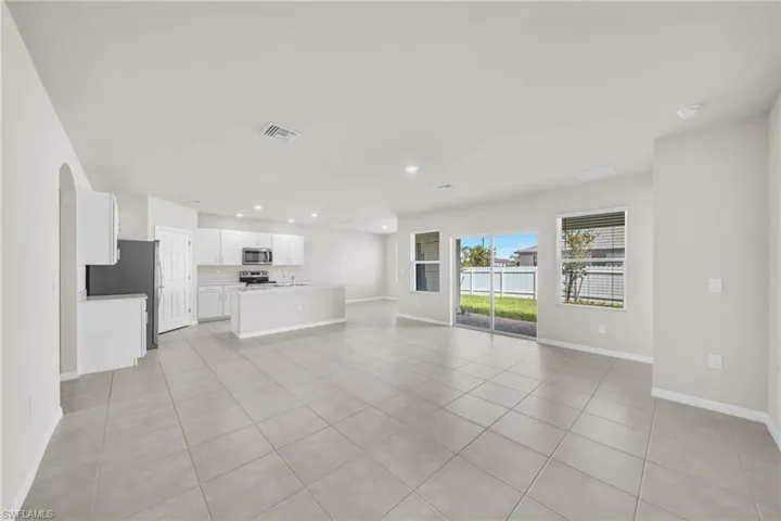 Unfurnished living room with light tile patterned flooring, recessed lighting, and arched walkways