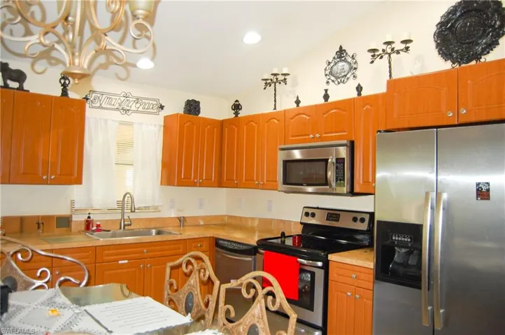 Kitchen with vaulted ceiling, sink, appliances with stainless steel finishes, and a chandelier