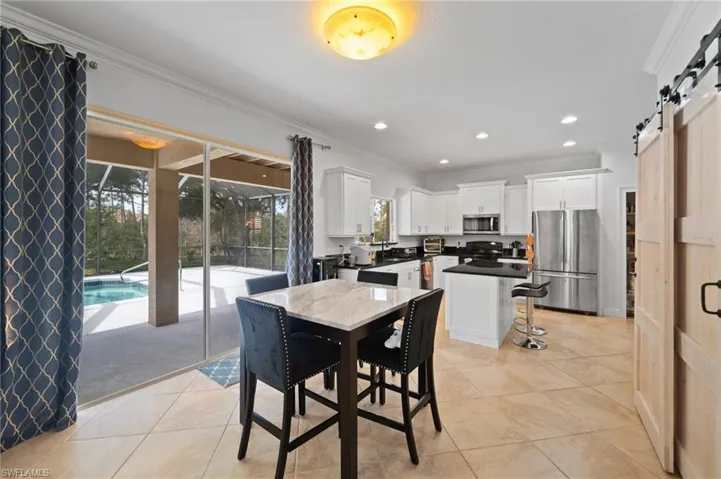 Tiled dining room featuring ornamental molding and a barn door