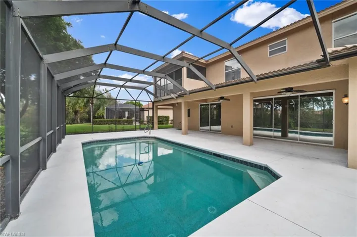 View of swimming pool with glass enclosure, ceiling fan, and a patio area