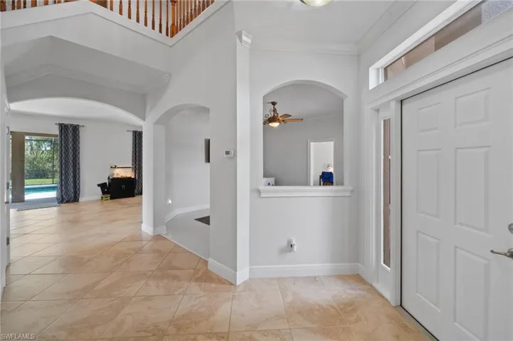 Hall with light tile patterned flooring and crown molding