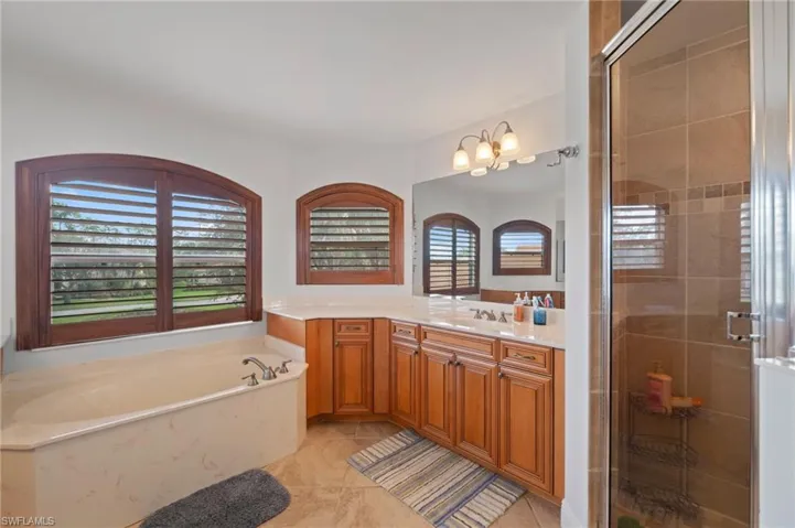 Bathroom with tile patterned flooring, shower with separate bathtub, a healthy amount of sunlight, and vanity
