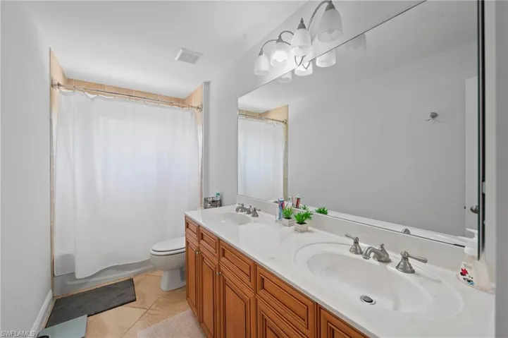 Full bathroom with tile patterned floors, vanity, toilet, and shower / tub combo