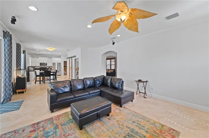 Tiled living room featuring ceiling fan and ornamental molding