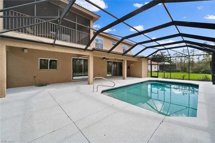 View of pool with ceiling fan, a yard, glass enclosure, and a patio area