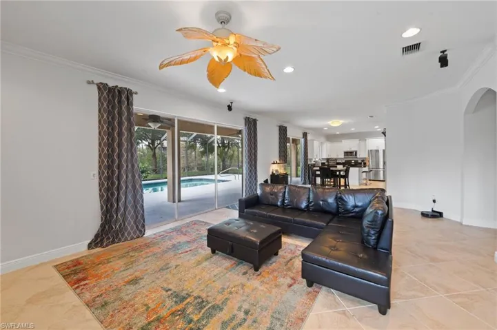 Tiled living room with ceiling fan and ornamental molding