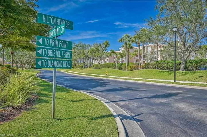 View of asphalt street featuring street lights, curbs, and sidewalks