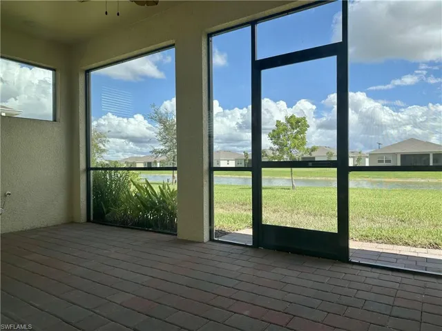 Unfurnished sunroom featuring a water view, ceiling fan, and a residential view