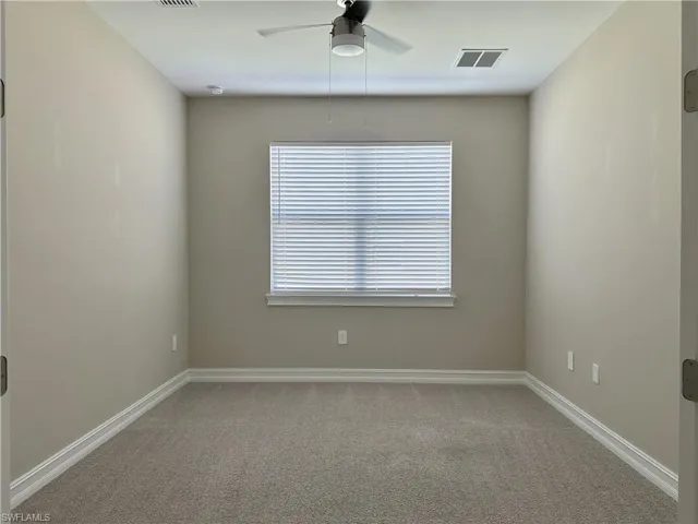 Empty room with carpet and a ceiling fan