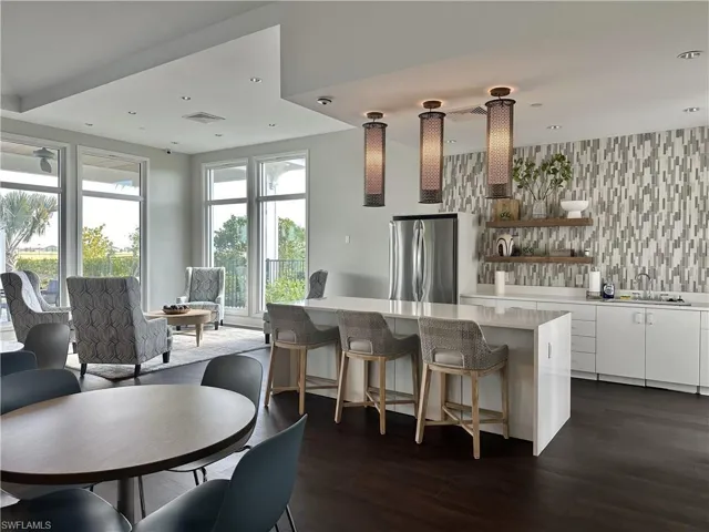 Kitchen with white cabinetry, open shelves, freestanding refrigerator, a kitchen breakfast bar, and light stone countertops