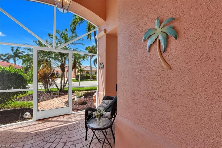 Screened porch with a circular brick paver floor, textured stucco wall, and a decorative palm tree wall accent