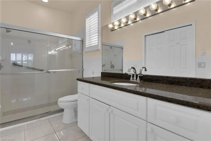 Bathroom vanity featuring a dark countertop, an undermount sink, and dual chrome faucets