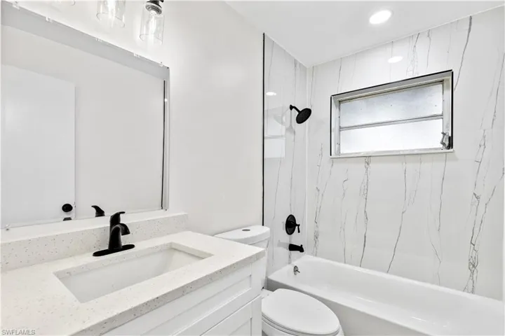 Full bathroom featuring toilet, tiled shower / bath combo, and vanity