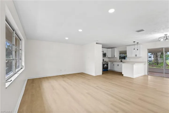Unfurnished living room featuring light hardwood / wood-style floors, sink, and plenty of natural light