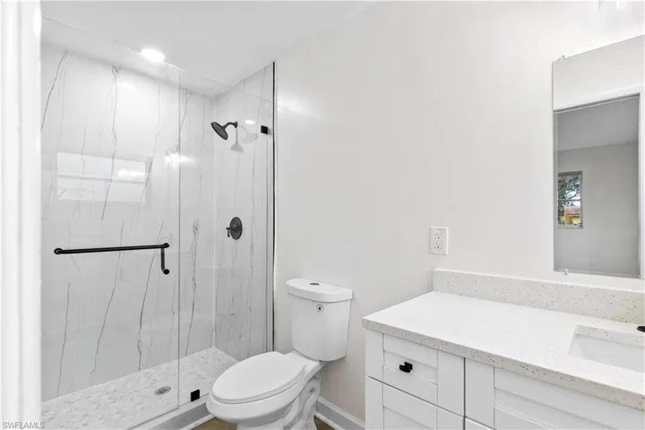 Bathroom with vanity, toilet, and an enclosed shower