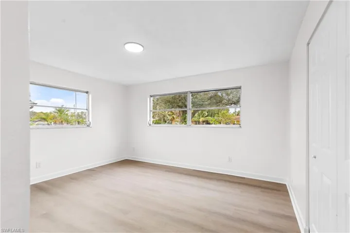 Unfurnished bedroom featuring light hardwood / wood-style flooring, multiple windows, and a closet