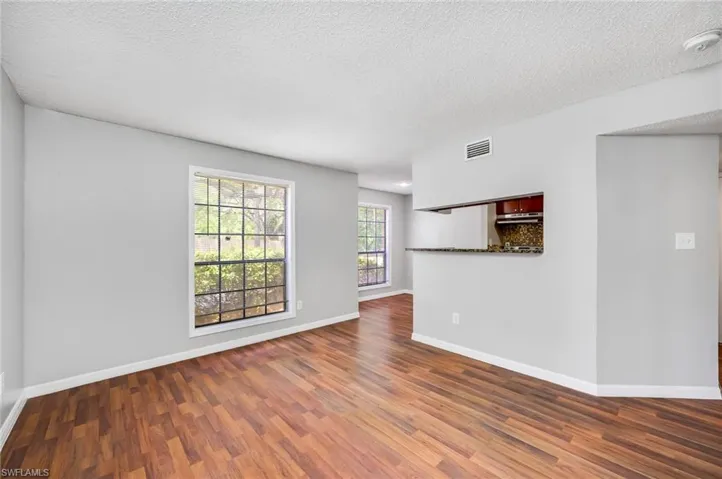 Unfurnished room with a textured ceiling and dark wood-type flooring