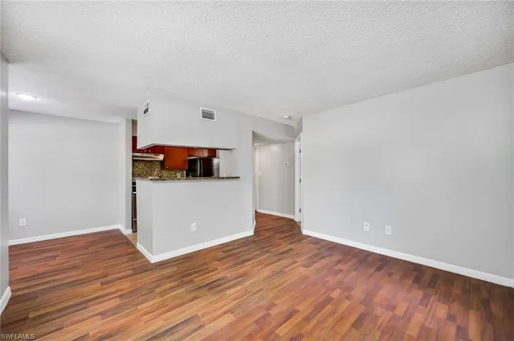 Unfurnished living room featuring dark wood-style floors and a textured ceiling