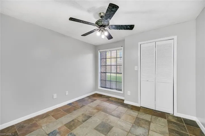 Unfurnished bedroom with a ceiling fan, stone finish floors, and a closet