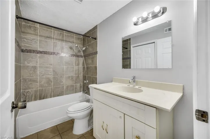 Bathroom featuring tub / shower combination, tile patterned floors, vanity, and a textured ceiling