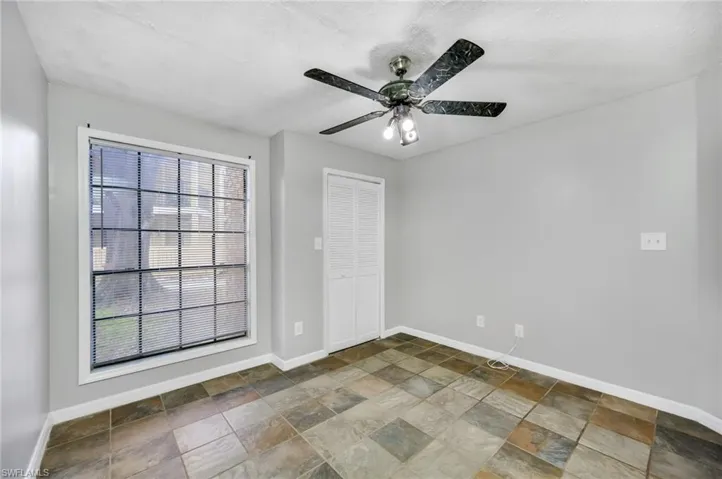 Unfurnished room with stone finish floors and a ceiling fan