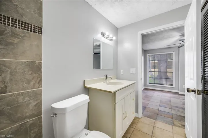 Bathroom with vanity, a textured ceiling, light tile patterned floors, and ceiling fan