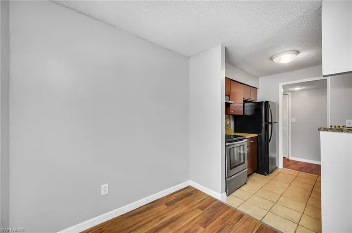 Kitchen featuring light wood finished floors, a textured ceiling, electric stove, backsplash, and brown cabinetry
