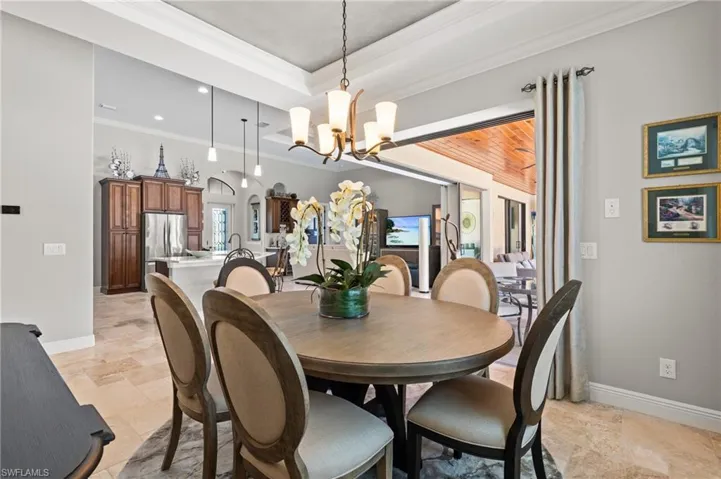 Dining space featuring a tray ceiling, a notable chandelier, ornamental molding, and baseboards