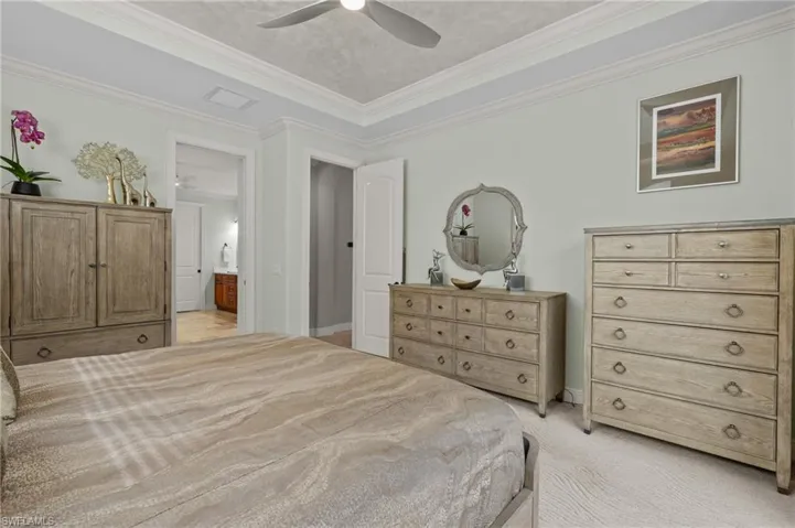 Primary Bedroom with light carpet, ensuite bathroom, crown molding, and ceiling fan