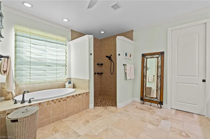 Primary Bathroom with baseboards, ornamental molding, walk in shower, a bath, and visible vents