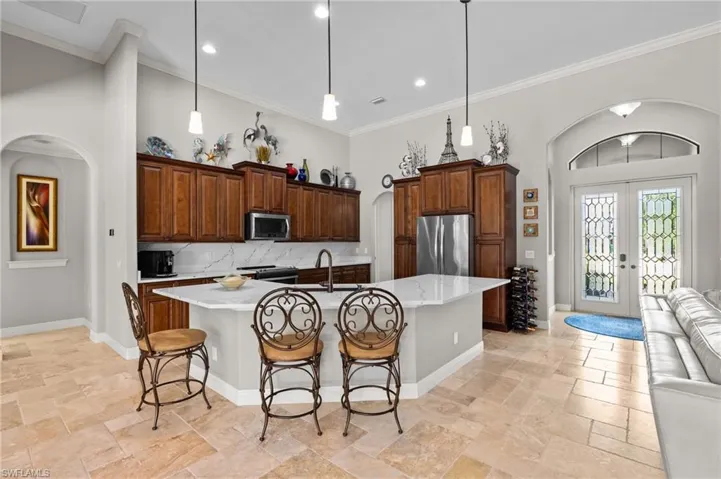 Kitchen featuring arched walkways, stainless steel appliances, french doors, baseboards, and stone tile flooring