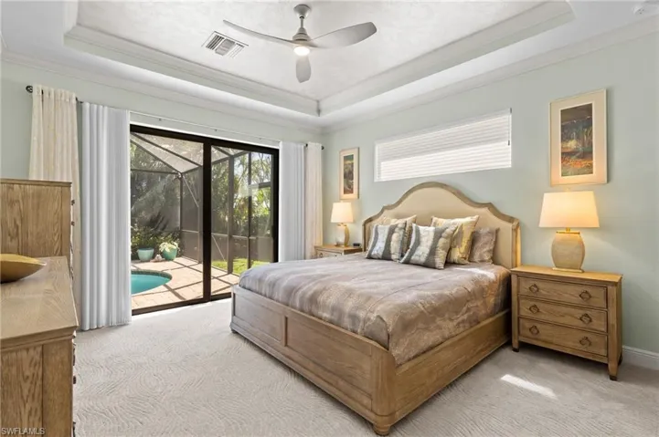 Primary bedroom featuring carpet, access to outside, a tray ceiling, and crown molding