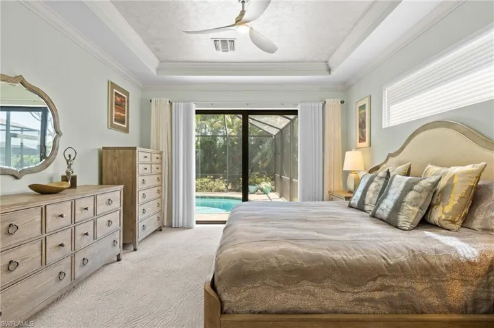 Primary Bedroom with light carpet, visible vents, a tray ceiling, and access to outside