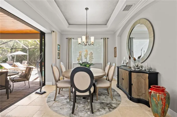 Dining area featuring crown molding, visible vents, a raised ceiling, baseboards, and a notable chandelier