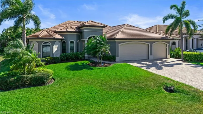 Mediterranean / spanish house with stucco siding, decorative driveway, a front yard, a tile roof, and an attached garage