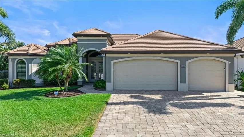 View of front of property featuring stucco siding, a front yard, a tile roof, a garage, and driveway