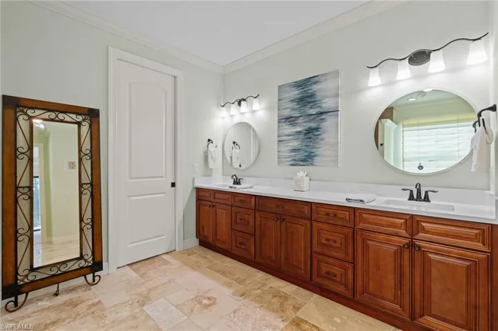 Primary bath with crown molding, double vanity, and a sink