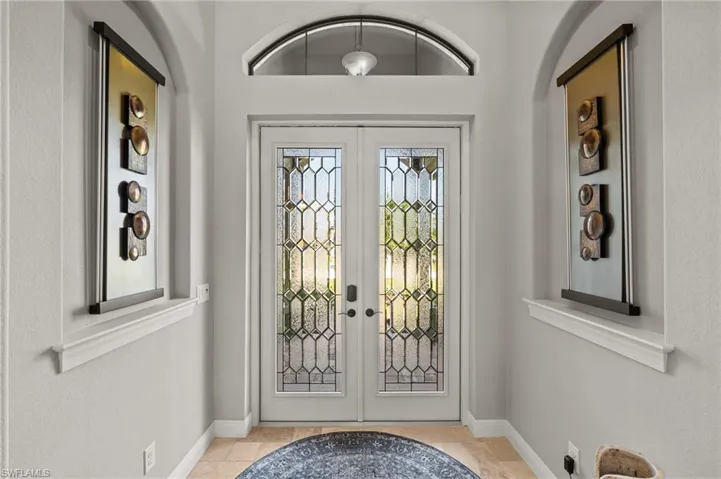 Tiled foyer with arched walkways, french doors, and baseboards