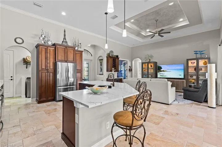 Kitchen with arched walkways, visible vents, freestanding refrigerator, and a raised ceiling