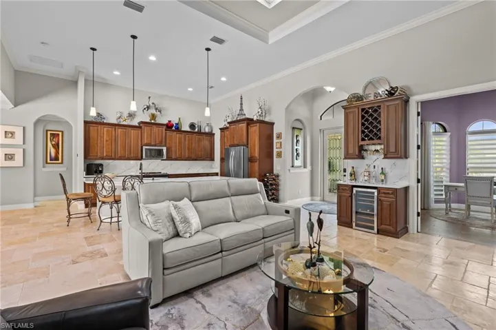 Living area featuring indoor wet bar, baseboards, visible vents, arched walkways, and stone tile floors