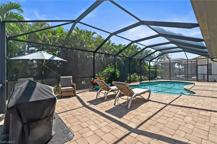Outdoor pool featuring grilling area, a patio, and glass enclosure