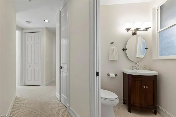 Half bath featuring vanity, a closet, and light colored carpet