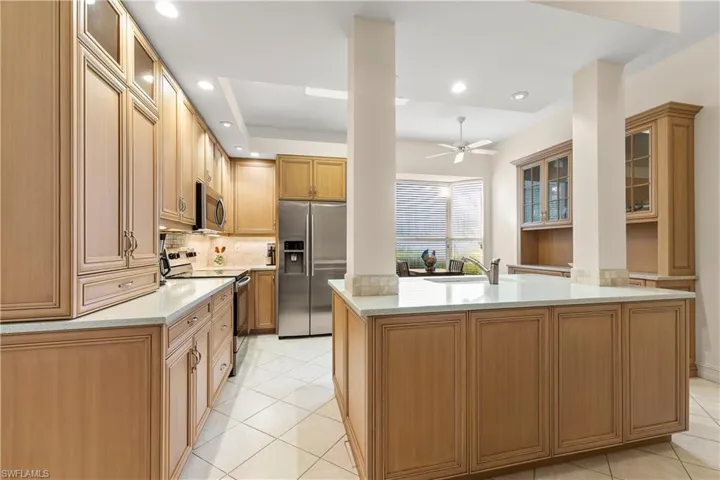 Kitchen featuring glass insert cabinets, appliances with stainless steel finishes, light stone countertops, recessed lighting, and light tile patterned flooring