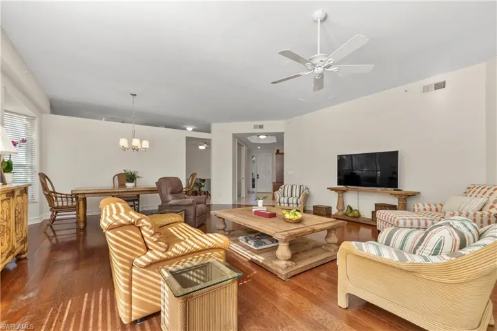 Living room with dark wood finished floors, a ceiling fan, and a chandelier