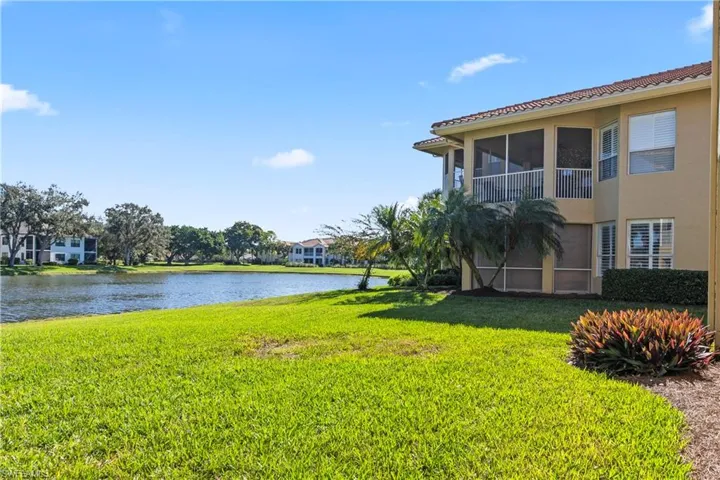 View of green lawn featuring a sunroom and a water view