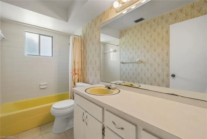 Full bathroom with shower / bath combination with curtain, toilet, vanity, and tile patterned floors
