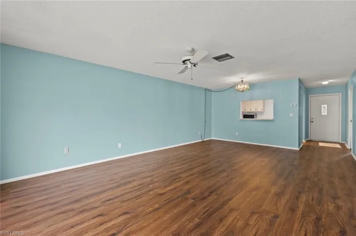 Unfurnished living room featuring a textured ceiling, ceiling fan with notable chandelier, and hardwood / wood-style floors